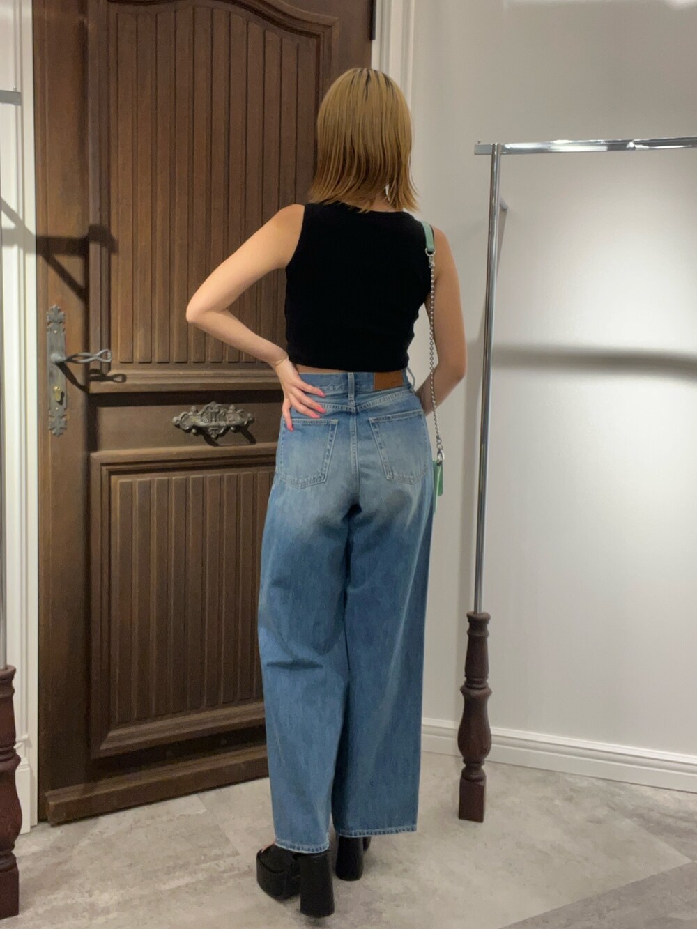 ブラック系のタンクトップ、ブルー系のデニムパンツ、グリーン系のショルダーバッグを着用したレディースの夏コーディネートの5枚目の写真