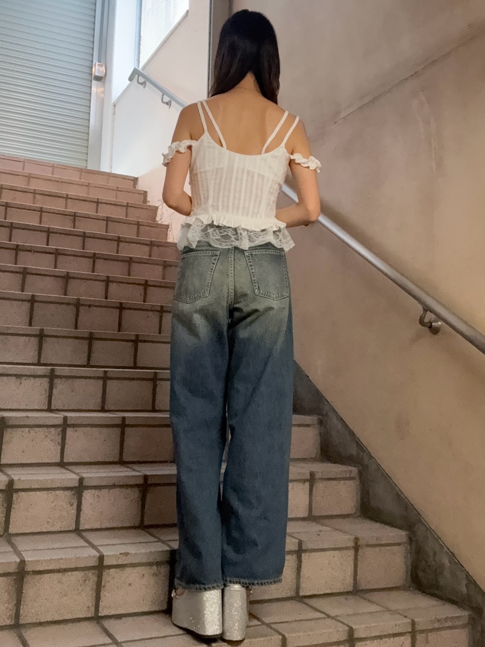 ホワイト系のキャミソール、ブルー系のデニムパンツ、シルバー系のサンダルを着用したレディースの春コーディネートの3枚目の写真