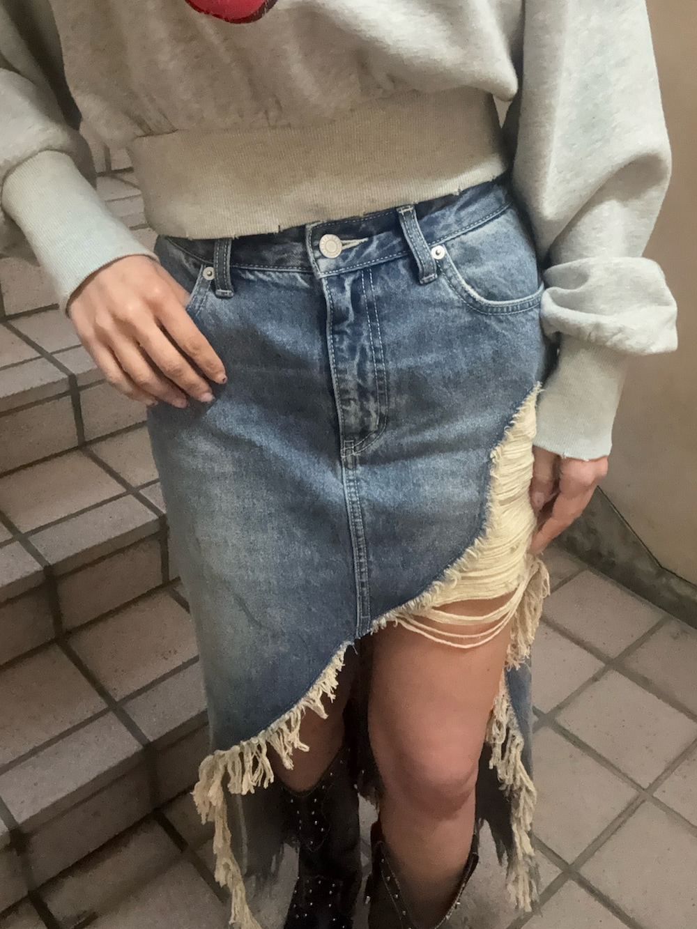 グレー系のスウェット、ブルー系のデニムスカート、ブラック系のキャップを着用したレディースの春コーディネートの6枚目の写真