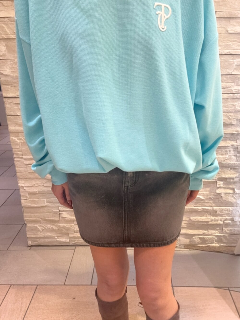 ブルー系のTシャツ/カットソー、ブラック系のデニムスカート、ブラウン系のブーツを着用したレディースの秋コーディネートの6枚目の写真