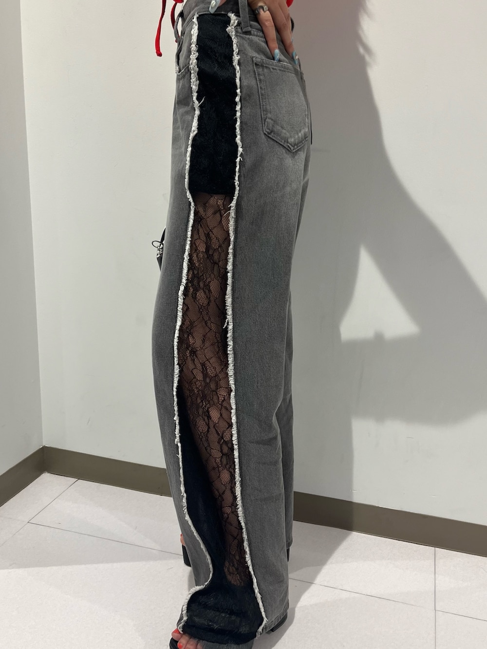 レッド系のタンクトップ、ブラック系のデニムパンツ、ブラック系のサンダルを着用したレディースの夏コーディネートの3枚目の写真