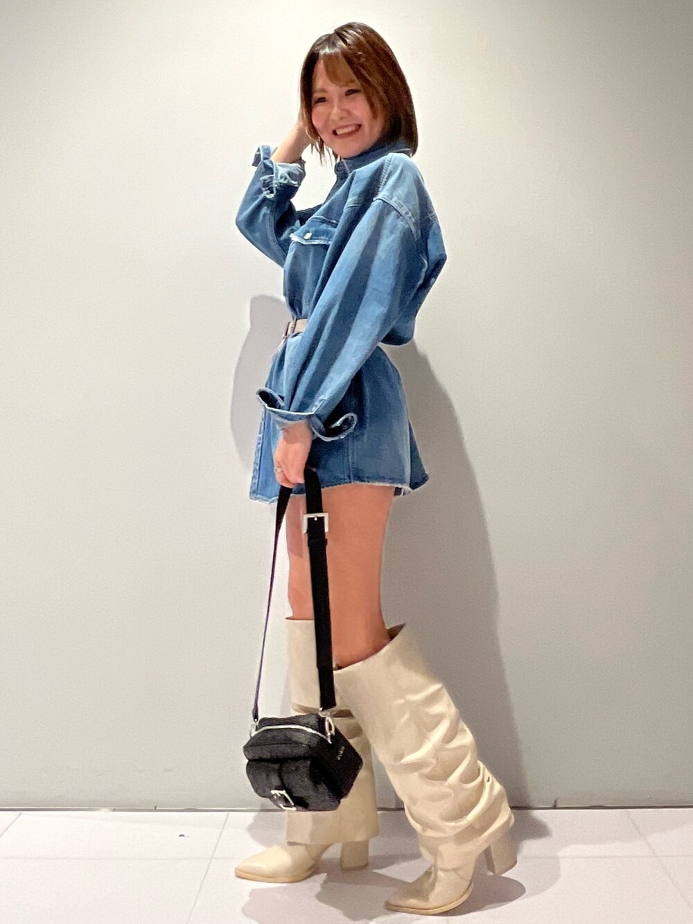 ブルー系のシャツ/ブラウス、ブラック系のショルダーバッグ、ホワイト系のブーツを着用したレディースの春コーディネートの2枚目の写真