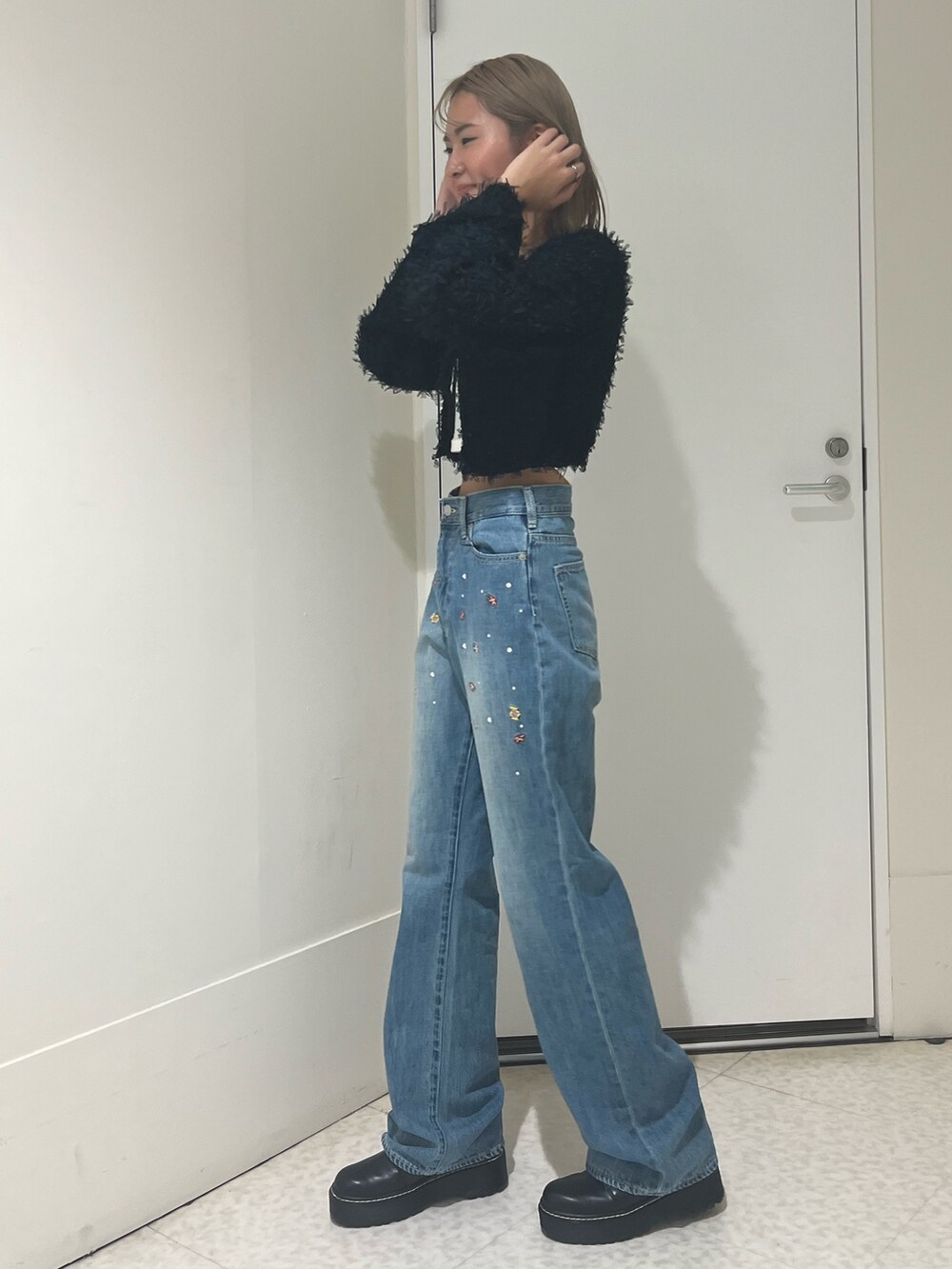 ブラック系のニット/セーター、ホワイト系のTシャツ/カットソー、ブルー系のデニムパンツを着用したレディースの秋コーディネートの2枚目の写真