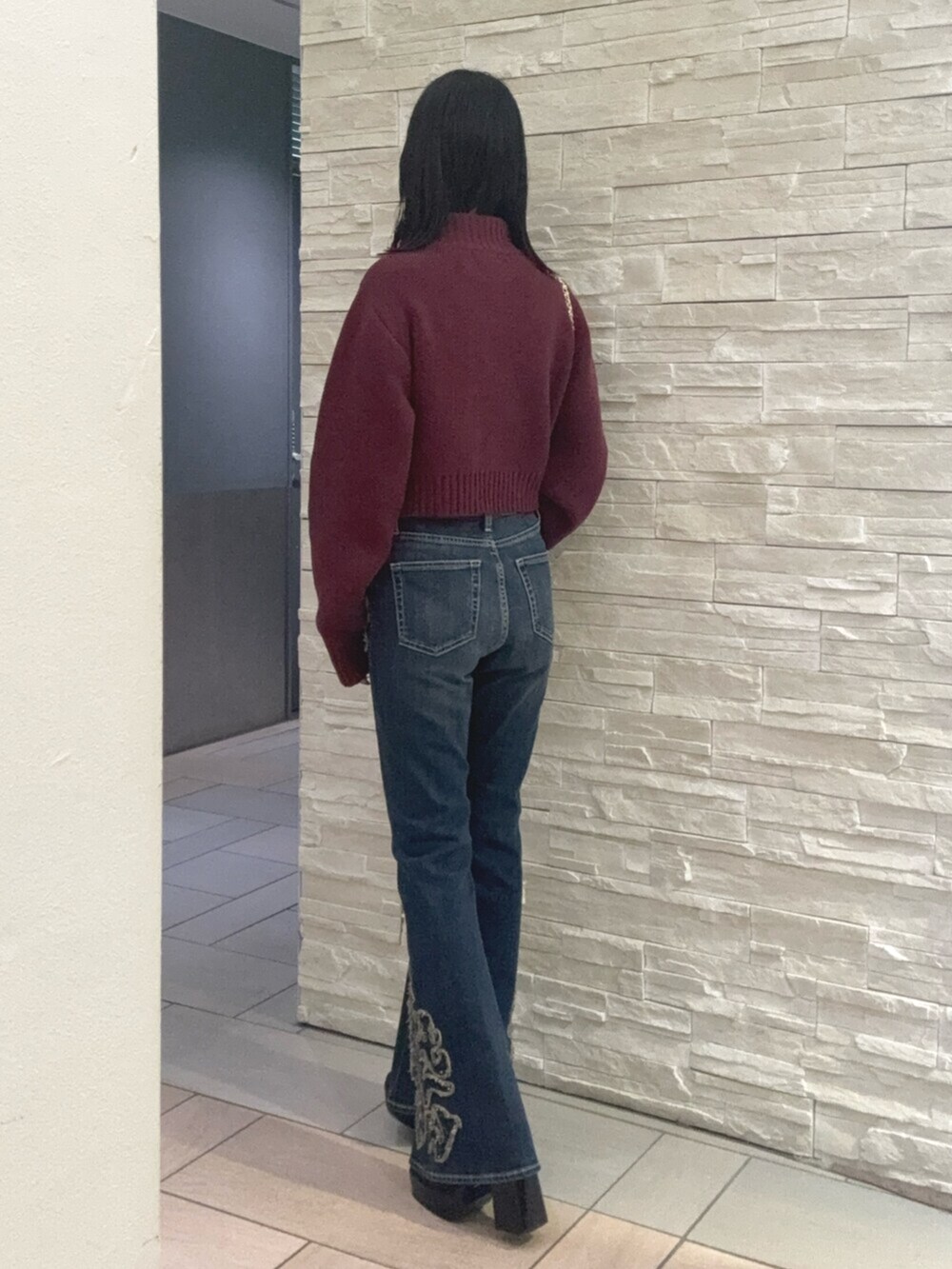 レッド系のニット/セーター、ブルー系のデニムパンツ、その他のブーツを着用したレディースの秋コーディネートの2枚目の写真