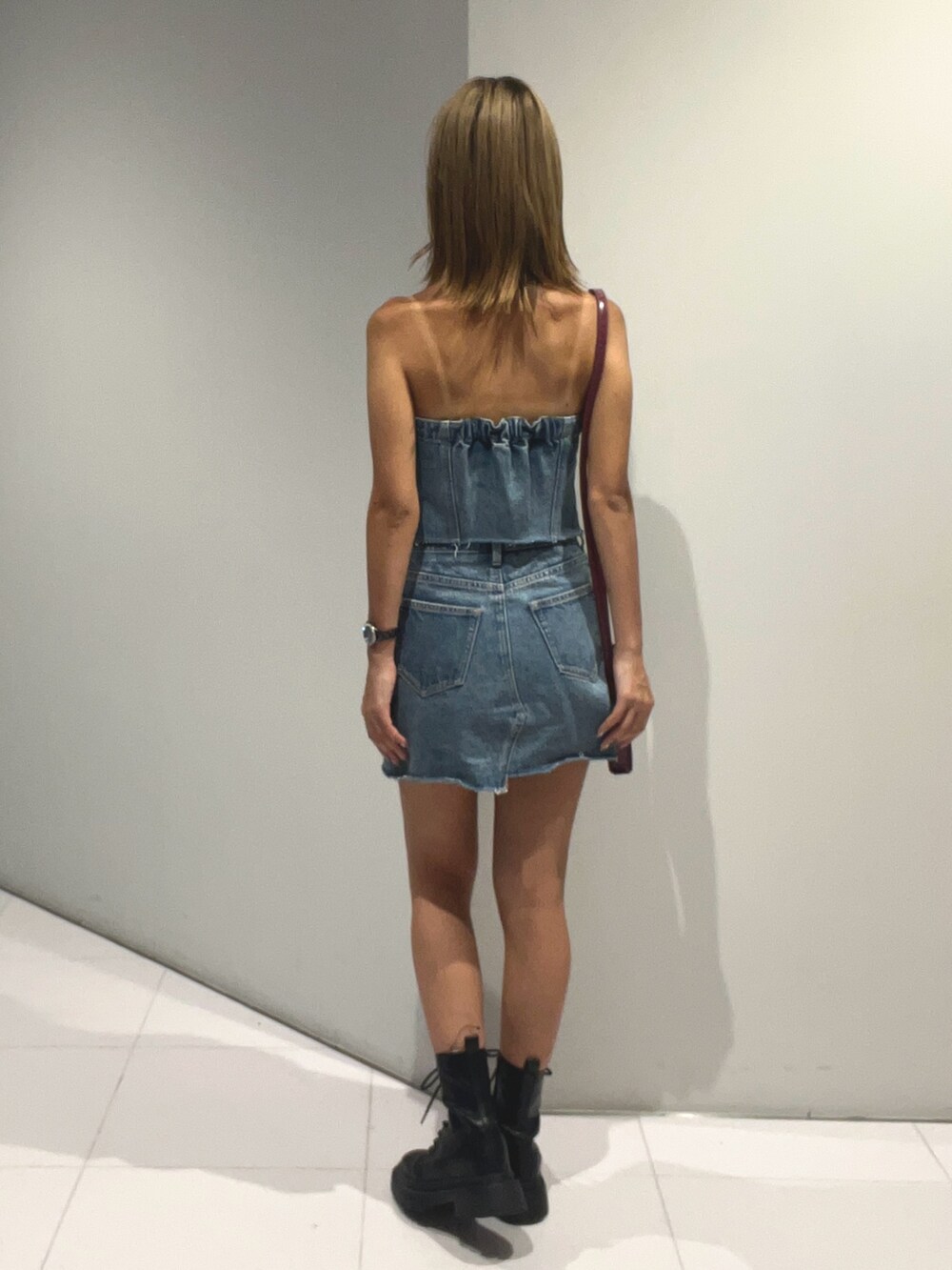 ブルー系のキャミソール、ブルー系のデニムスカート、ブラック系のブーツを着用したレディースの夏コーディネートの3枚目の写真