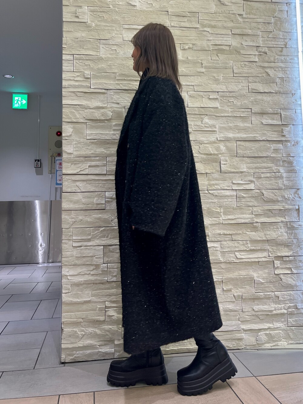 ブラック系のチェスターコート、ブラック系のつなぎ/オールインワン、ブラック系のブーツを着用したレディースの冬コーディネートの3枚目の写真