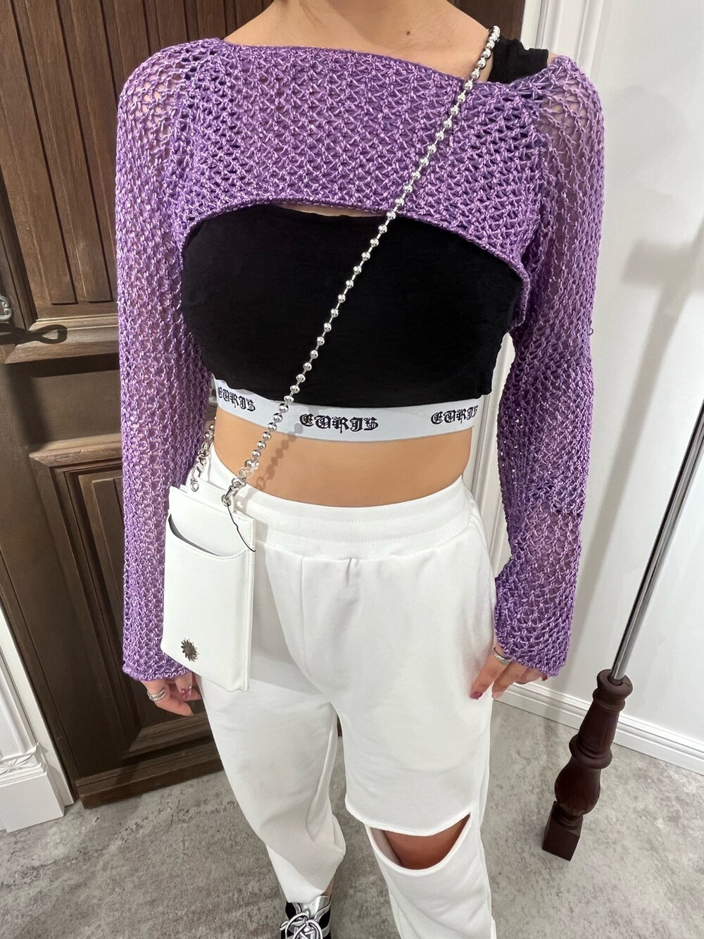 パープル系のニット/セーター、ブラック系のキャミソール、ホワイト系のショルダーバッグを着用したレディースの春コーディネートの3枚目の写真