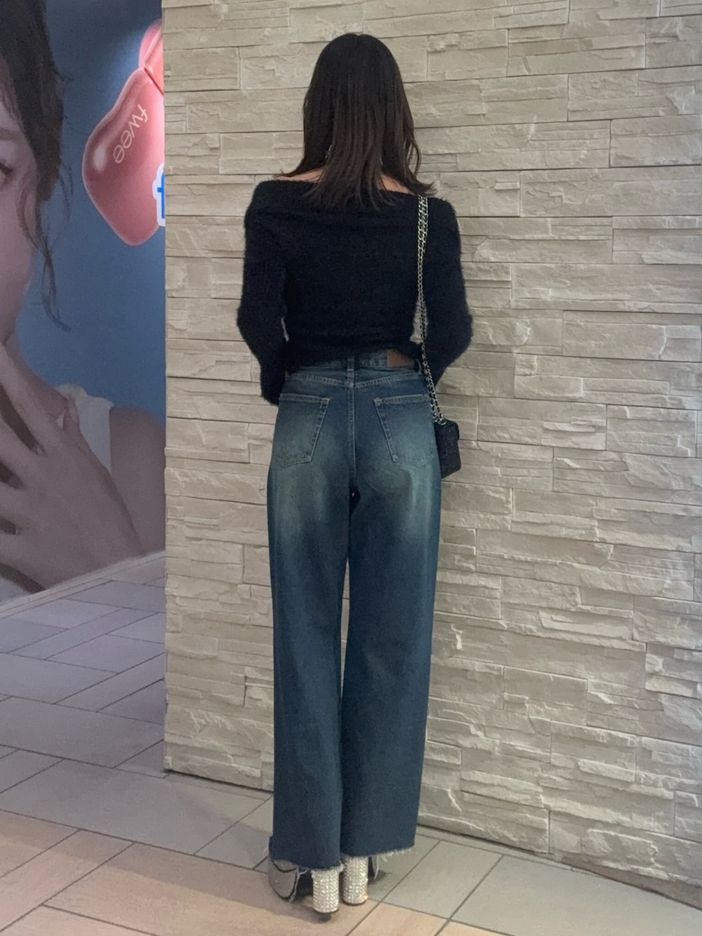 ブラック系のニット/セーター、ブルー系のデニムパンツ、ブラック系のショルダーバッグを着用したレディースの冬コーディネートの3枚目の写真