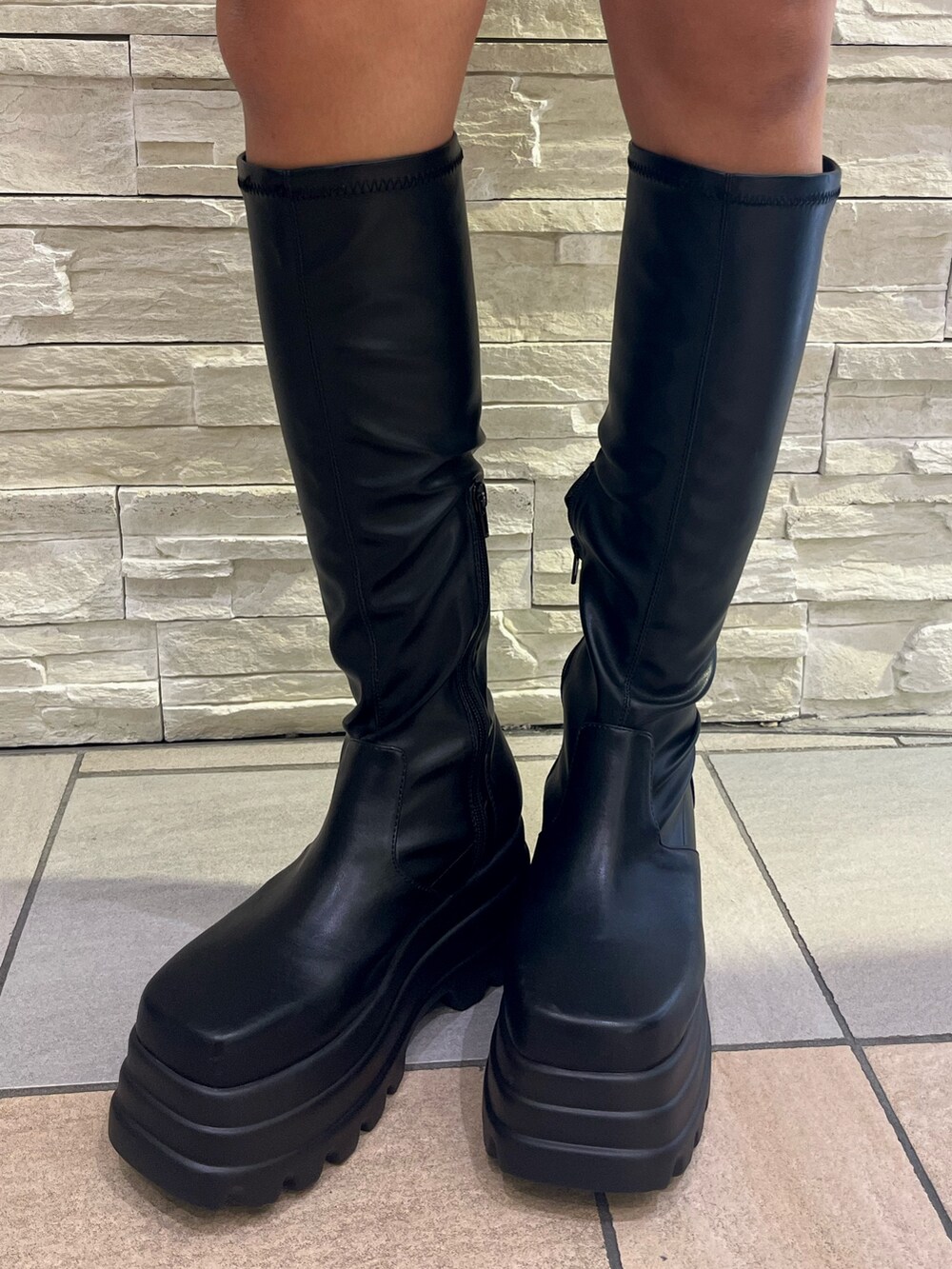 ブラック系のチェスターコート、ブラック系のつなぎ/オールインワン、ブラック系のブーツを着用したレディースの冬コーディネートの10枚目の写真