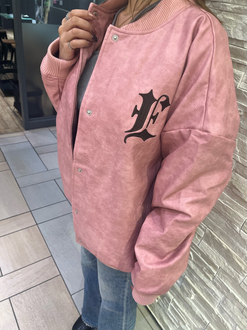 ピンク系のスタジャン、グレー系のTシャツ/カットソー、ブルー系のデニムパンツを着用したレディースの冬コーディネートの4枚目の写真