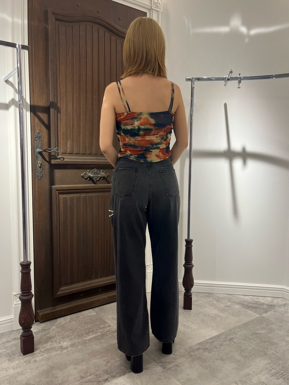 オレンジ系のキャミソール、ブラック系のデニムパンツ、ゴールド系のネックレスを着用したレディースの春コーディネートの3枚目の写真