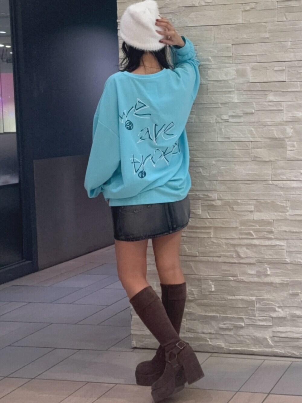 ブルー系のTシャツ/カットソー、ブラック系のデニムスカート、ブラウン系のブーツを着用したレディースの秋コーディネートの2枚目の写真