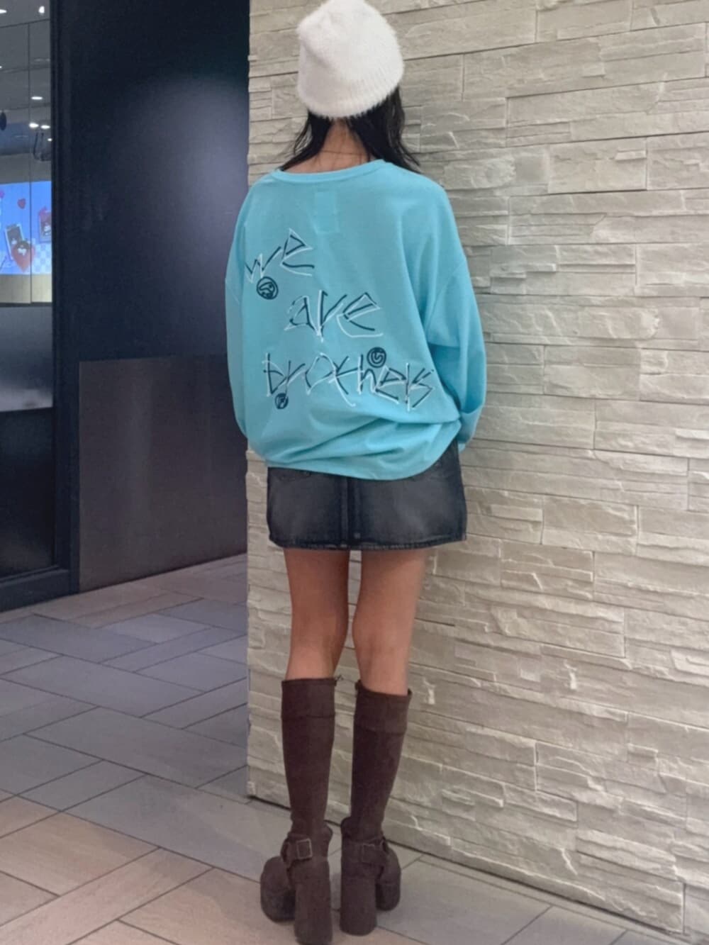 ブルー系のTシャツ/カットソー、ブラック系のデニムスカート、ブラウン系のブーツを着用したレディースの秋コーディネートの3枚目の写真