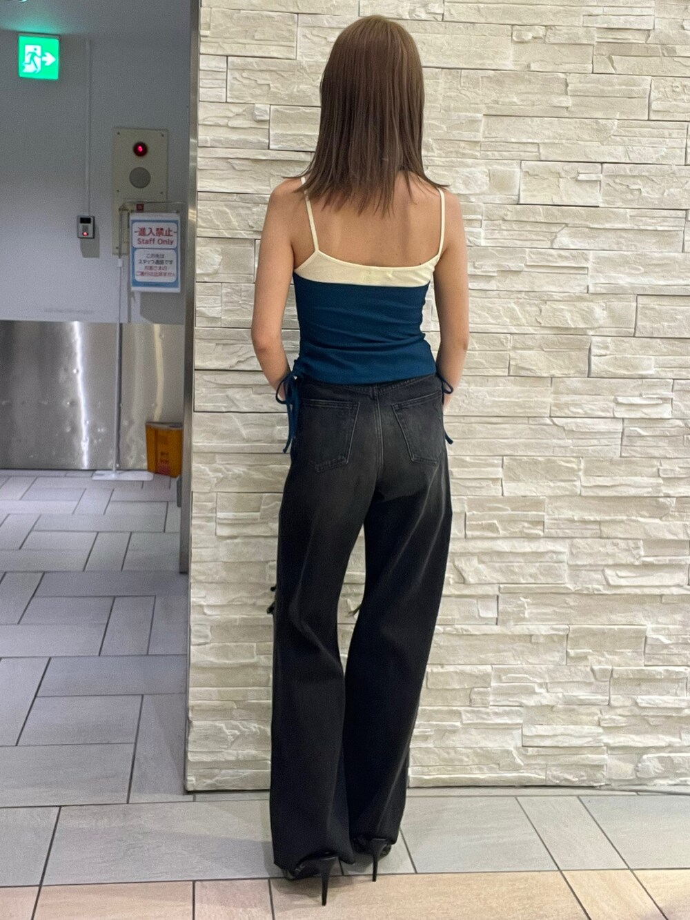 ブルー系のタンクトップ、ブラック系のデニムパンツ、グリーン系のサンダルを着用したレディースの春コーディネートの3枚目の写真