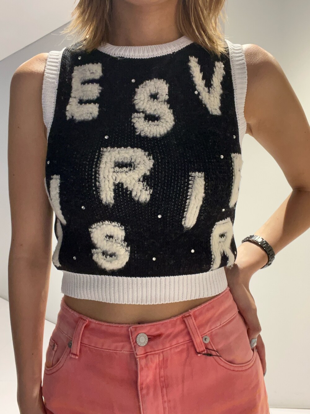 ブラック系のタンクトップ、ピンク系のデニムパンツ、ブラック系のサンダルを着用したレディースの夏コーディネートの2枚目の写真