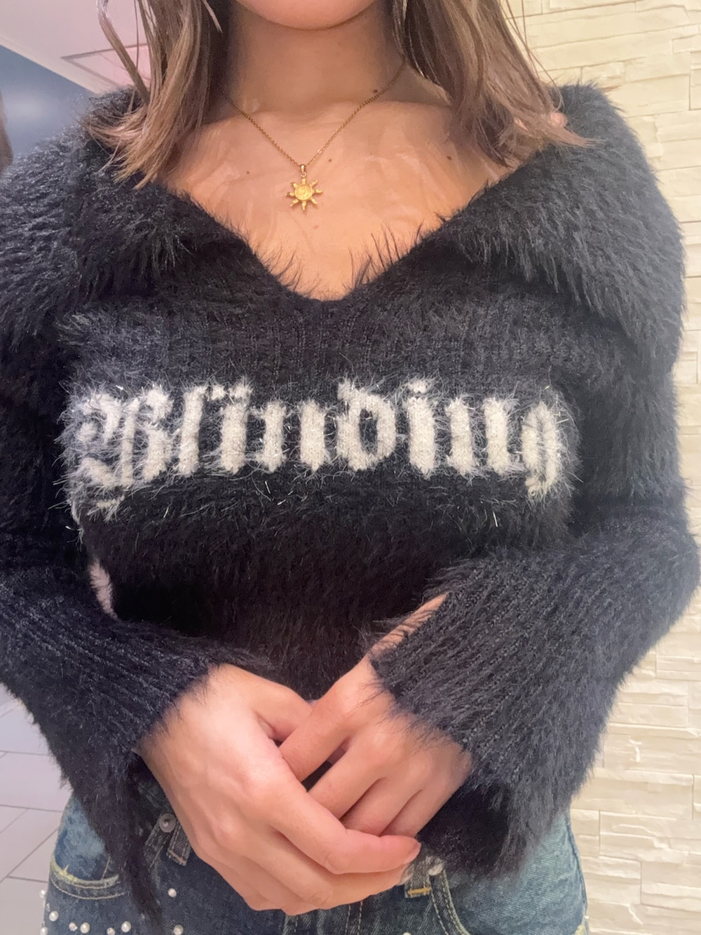 ブラック系のニット/セーター、ブルー系のデニムパンツ、ブラック系のショルダーバッグを着用したレディースの冬コーディネートの4枚目の写真