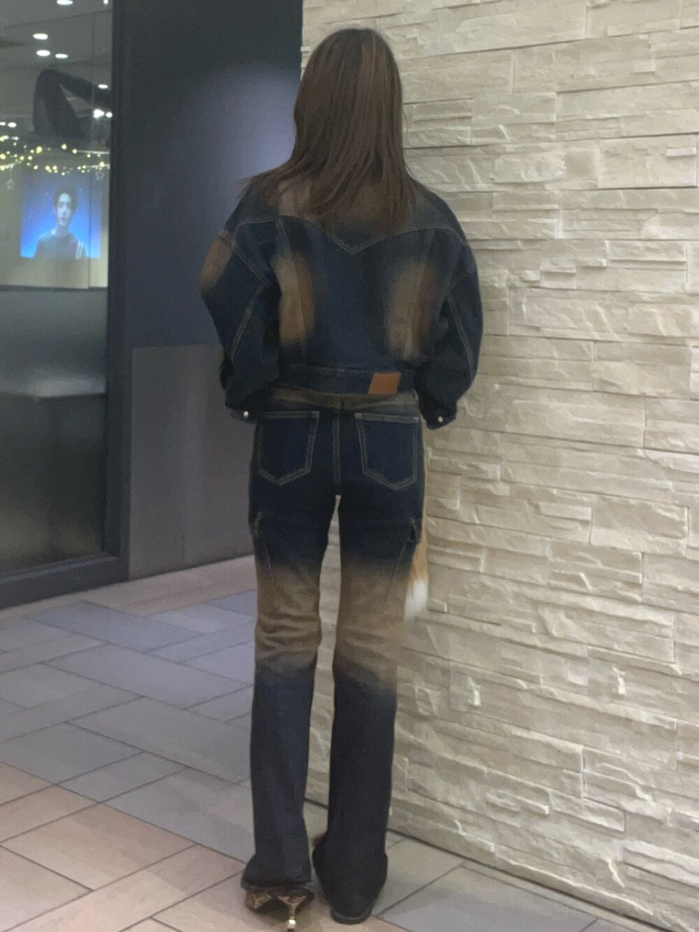 ブルー系のデニムジャケット、ブルー系のデニムパンツ、ブラウン系のタンクトップを着用したレディースの秋コーディネートの3枚目の写真