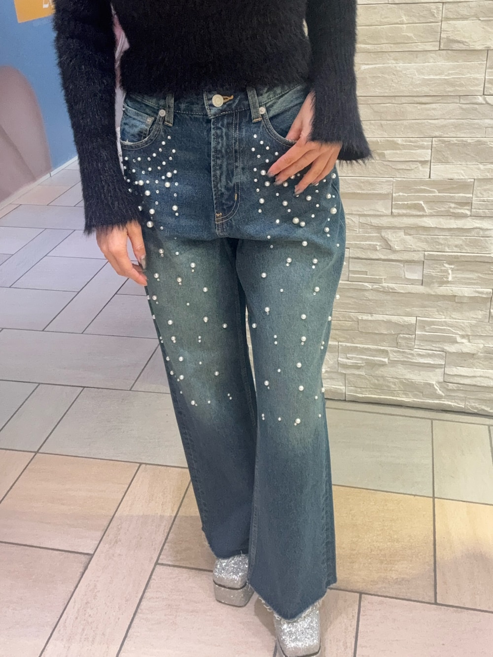 ブラック系のニット/セーター、ブルー系のデニムパンツ、ブラック系のショルダーバッグを着用したレディースの冬コーディネートの5枚目の写真