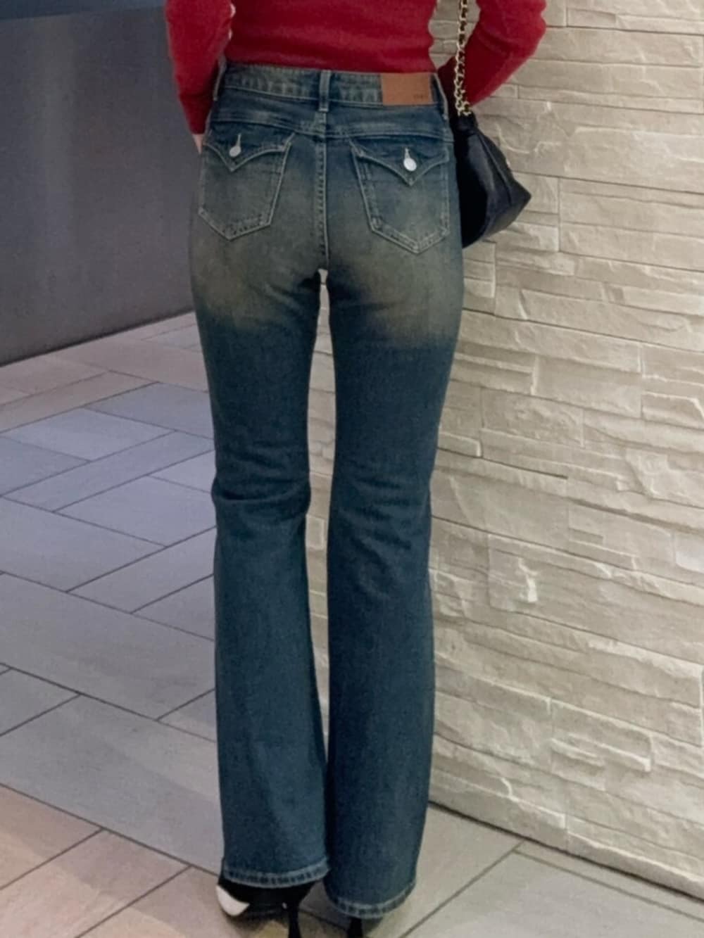 レッド系のニット/セーター、ブルー系のデニムパンツ、ブラック系のパンプスを着用したレディースの秋コーディネートの3枚目の写真