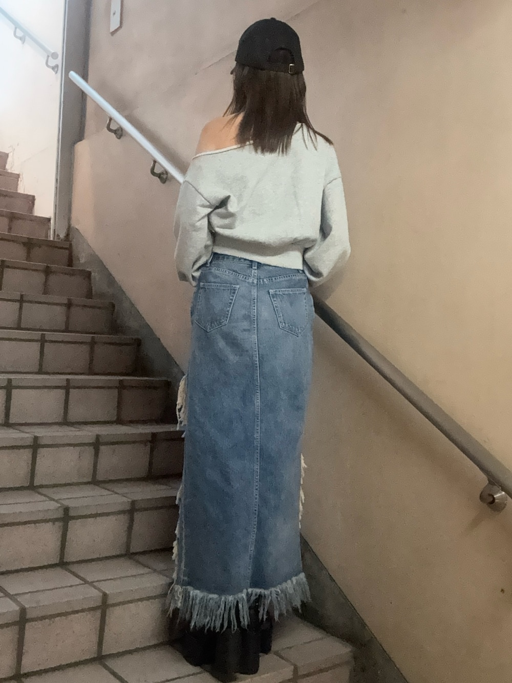 グレー系のスウェット、ブルー系のデニムスカート、ブラック系のキャップを着用したレディースの春コーディネートの3枚目の写真