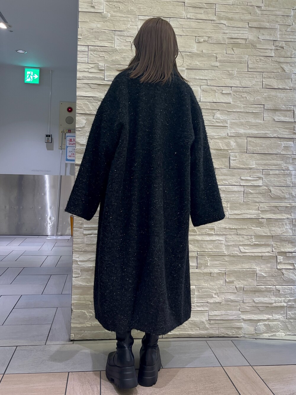 ブラック系のチェスターコート、ブラック系のつなぎ/オールインワン、ブラック系のブーツを着用したレディースの冬コーディネートの5枚目の写真