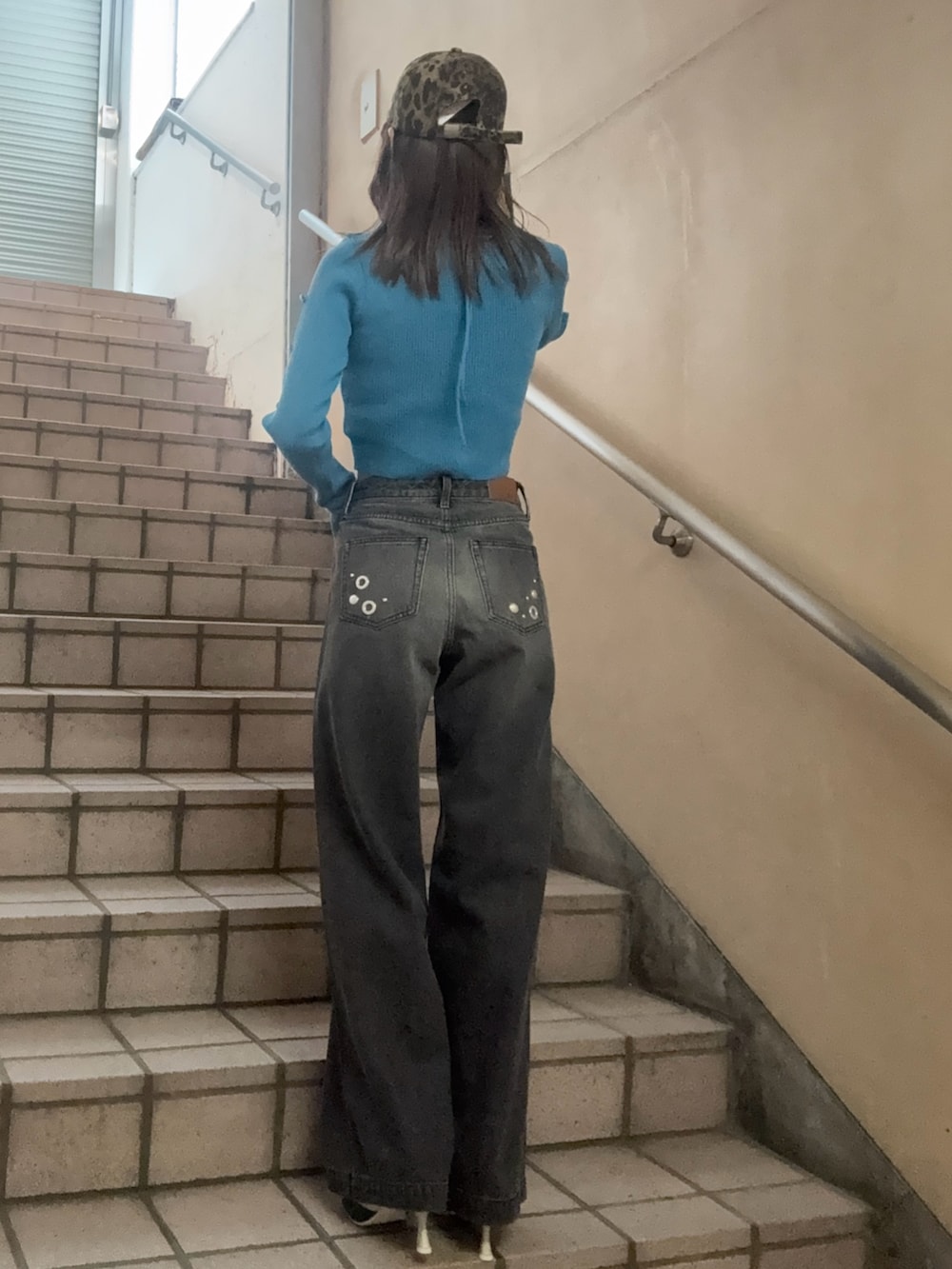 ブルー系のニット/セーター、ブラック系のデニムパンツ、シルバー系のパンプスを着用したレディースの春コーディネートの3枚目の写真