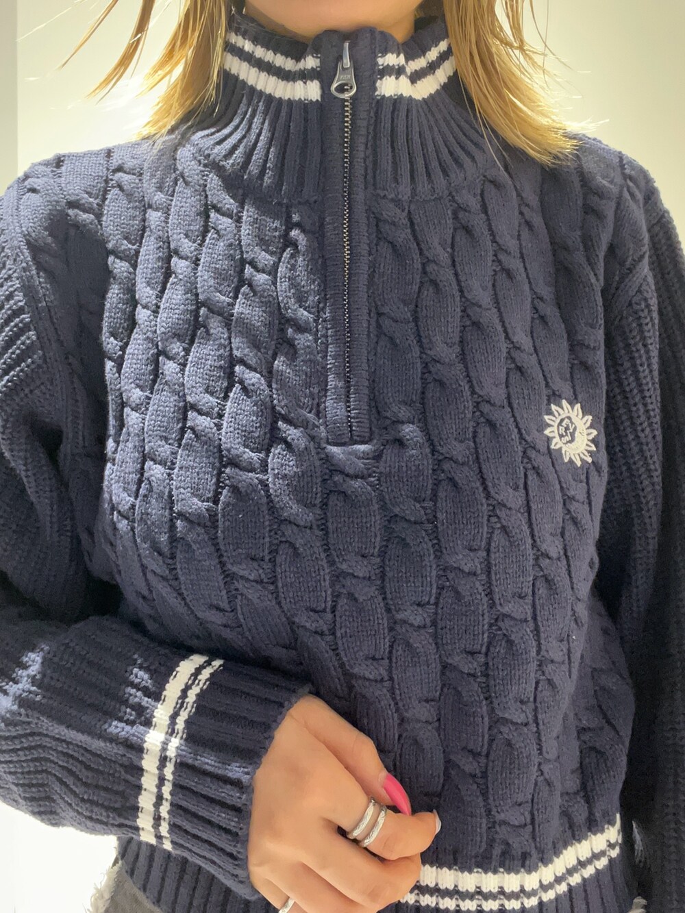 ブルー系のニット/セーター、ブラック系のショルダーバッグ、ブラック系のデニムパンツを着用したレディースの夏コーディネートの2枚目の写真