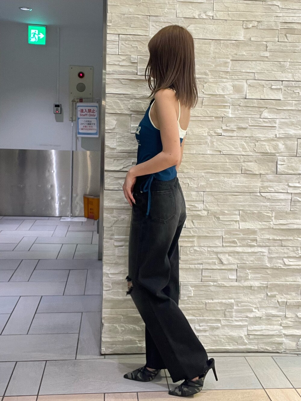 ブルー系のタンクトップ、ブラック系のデニムパンツ、グリーン系のサンダルを着用したレディースの春コーディネートの2枚目の写真