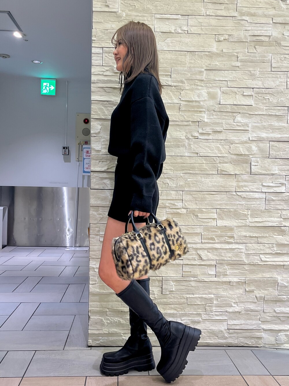 ブラック系のチェスターコート、ブラック系のつなぎ/オールインワン、ブラック系のブーツを着用したレディースの冬コーディネートの4枚目の写真