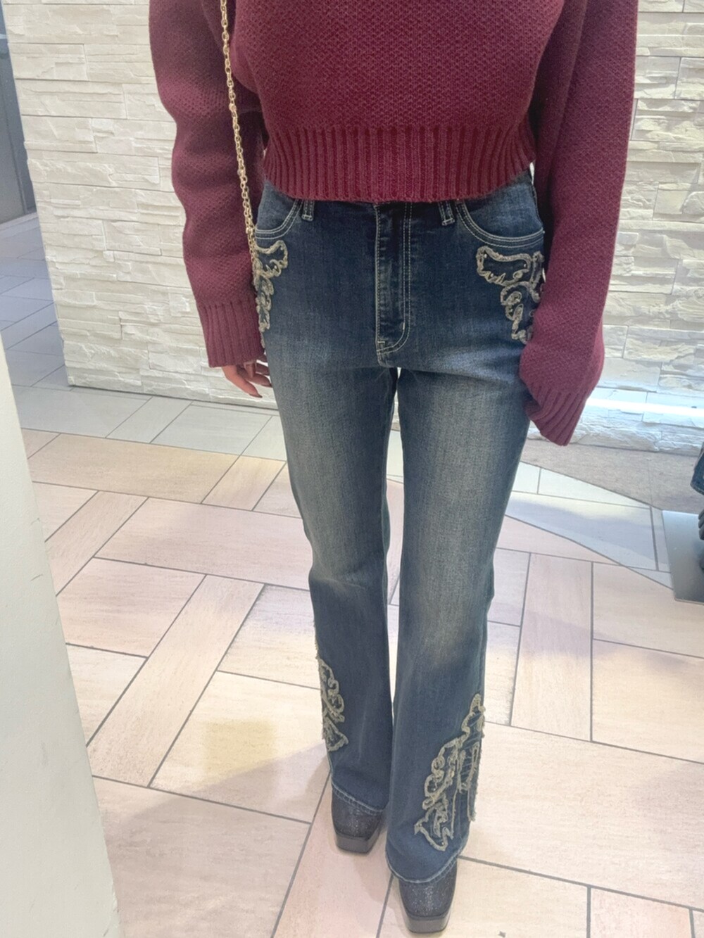 レッド系のニット/セーター、ブルー系のデニムパンツ、その他のブーツを着用したレディースの秋コーディネートの5枚目の写真