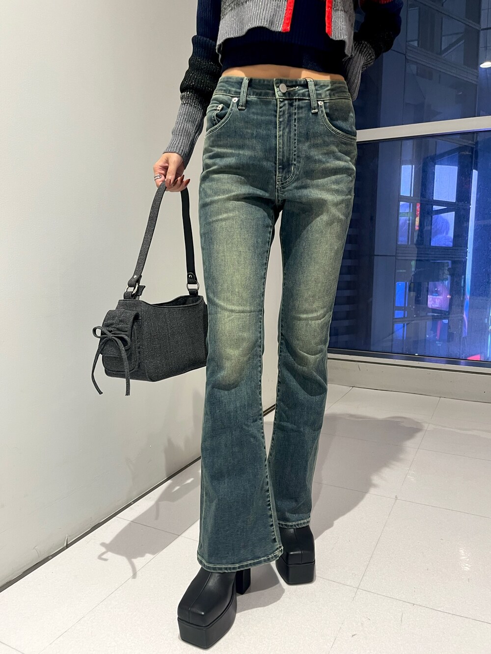 レッド系のニット/セーター、ブルー系のデニムパンツ、ブラック系のハンドバッグを着用したレディースの秋コーディネートの5枚目の写真