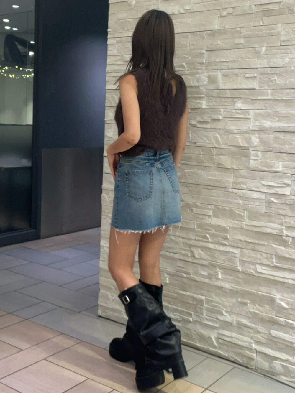 ブラウン系のタンクトップ、ブルー系のデニムスカート、ブラック系のブーツを着用したレディースの夏コーディネートの2枚目の写真