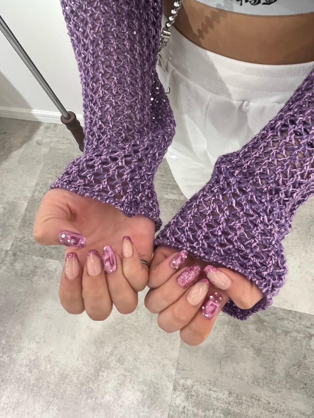 パープル系のニット/セーター、ブラック系のキャミソール、ホワイト系のショルダーバッグを着用したレディースの春コーディネートの6枚目の写真