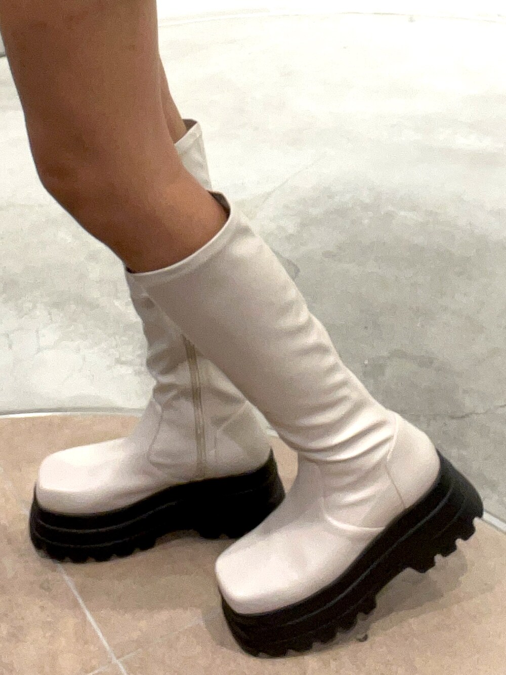 ブルー系のニット/セーター、ホワイト系のショルダーバッグ、ホワイト系のブーツを着用したレディースの秋コーディネートの4枚目の写真