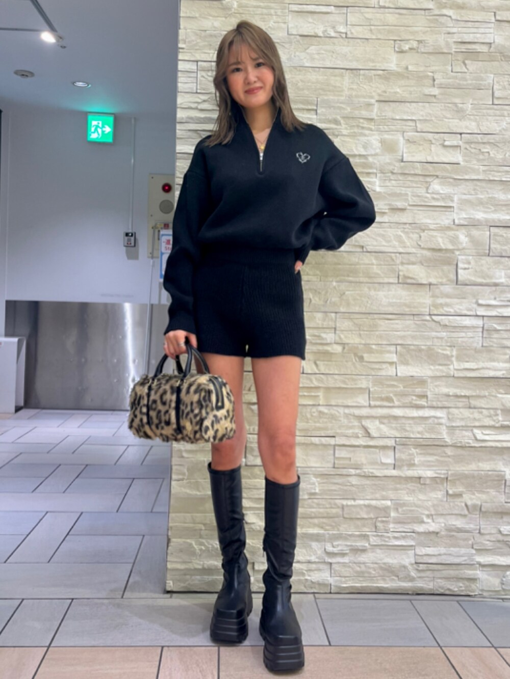 ブラック系のチェスターコート、ブラック系のつなぎ/オールインワン、ブラック系のブーツを着用したレディースの冬コーディネートの2枚目の写真