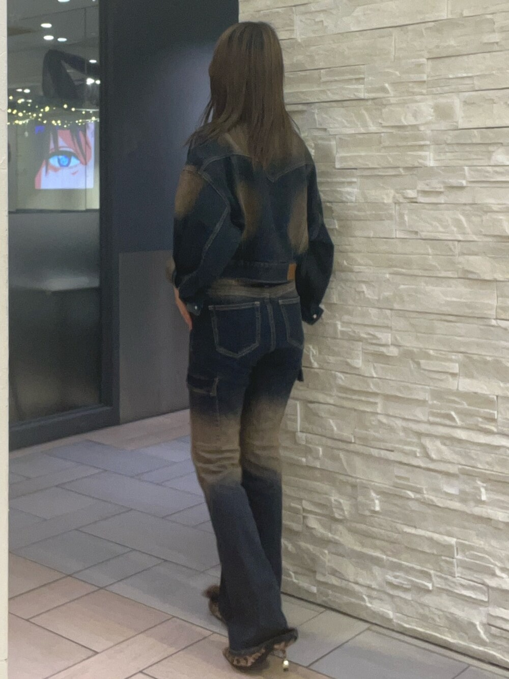 ブルー系のデニムジャケット、ブルー系のデニムパンツ、ブラウン系のタンクトップを着用したレディースの秋コーディネートの2枚目の写真