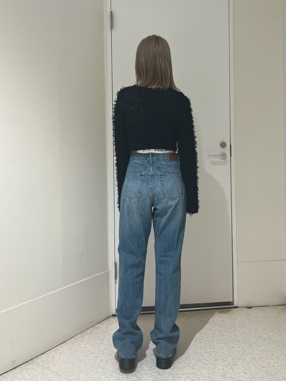 ブラック系のニット/セーター、ホワイト系のTシャツ/カットソー、ブルー系のデニムパンツを着用したレディースの秋コーディネートの3枚目の写真