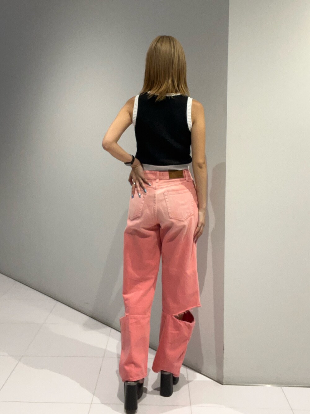 ブラック系のタンクトップ、ピンク系のデニムパンツ、ブラック系のサンダルを着用したレディースの夏コーディネートの6枚目の写真