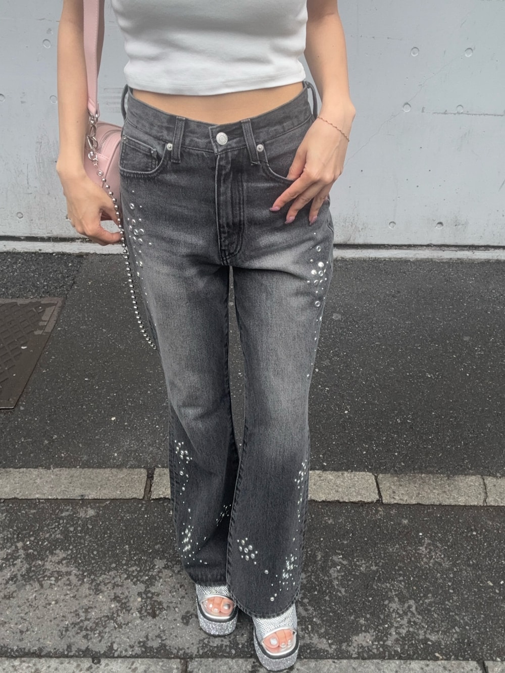 ホワイト系のタンクトップ、ブラック系のデニムパンツ、ピンク系のショルダーバッグを着用したレディースの夏コーディネートの5枚目の写真