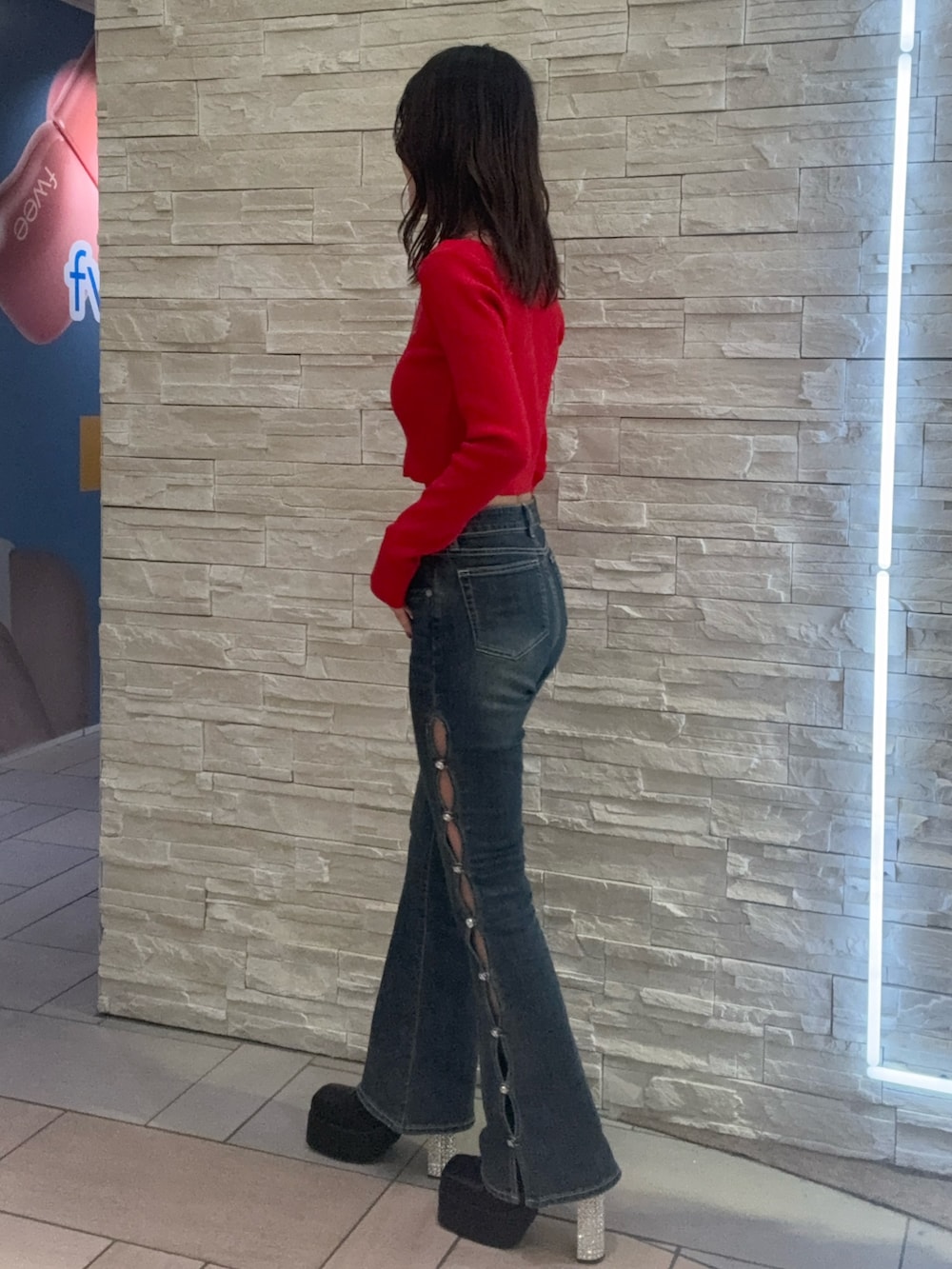 レッド系のニット/セーター、ブルー系のデニムパンツ、ブラック系のブーツを着用したレディースの冬コーディネートの2枚目の写真