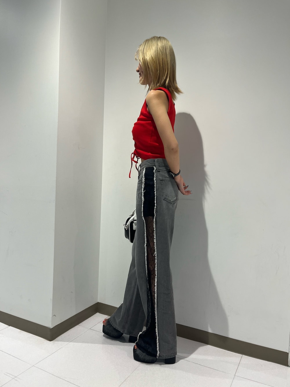 レッド系のタンクトップ、ブラック系のデニムパンツ、ブラック系のサンダルを着用したレディースの夏コーディネートの4枚目の写真