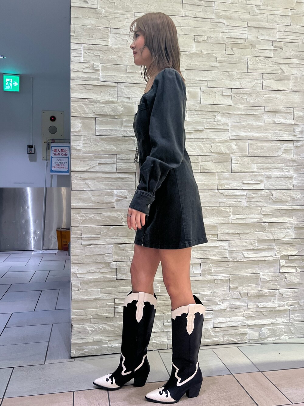 ブラック系のワンピース、ホワイト系のショルダーバッグ、その他のブーツを着用したレディースの冬コーディネートの2枚目の写真