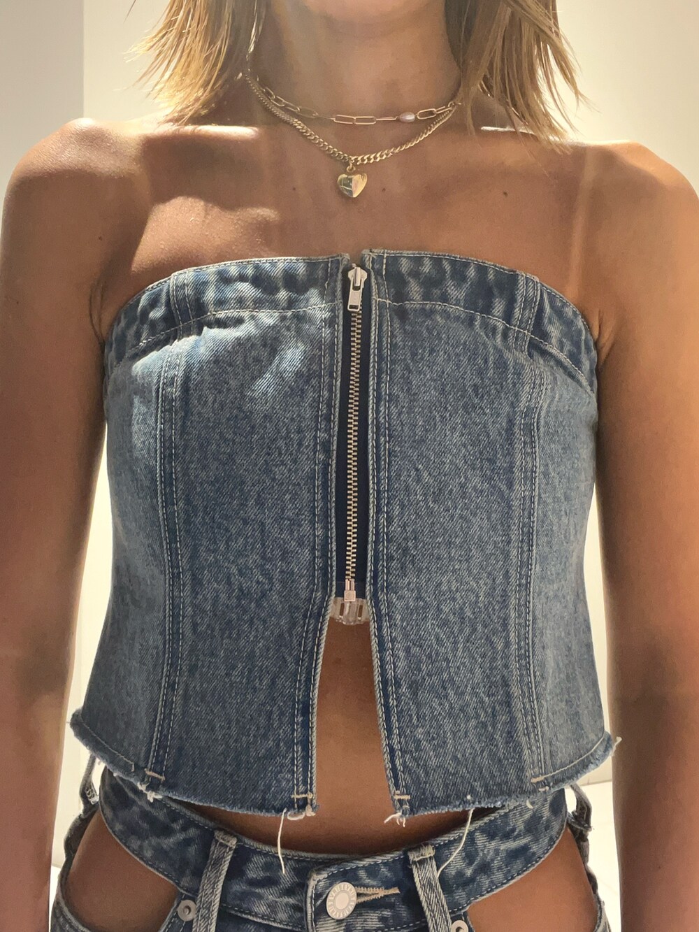 ブルー系のキャミソール、ブルー系のデニムスカート、ブラック系のブーツを着用したレディースの夏コーディネートの4枚目の写真