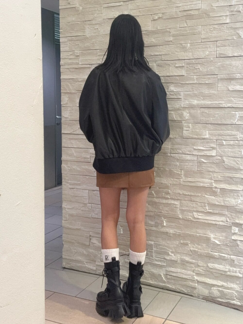 ブラック系のブルゾン、ホワイト系のTシャツ/カットソー、ブラウン系のスカートを着用したレディースの秋コーディネートの3枚目の写真