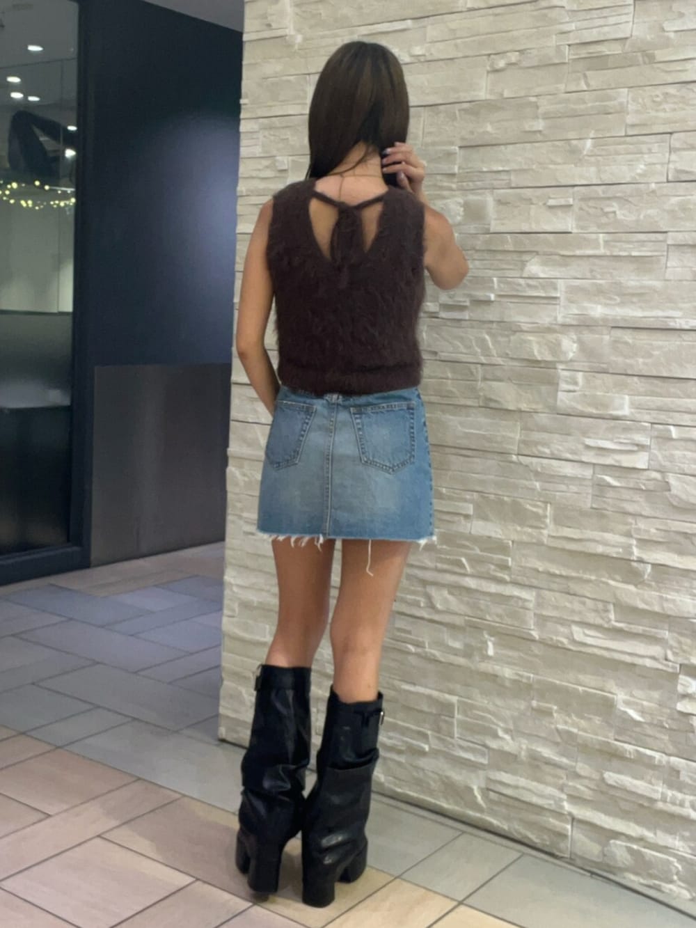 ブラウン系のタンクトップ、ブルー系のデニムスカート、ブラック系のブーツを着用したレディースの夏コーディネートの3枚目の写真