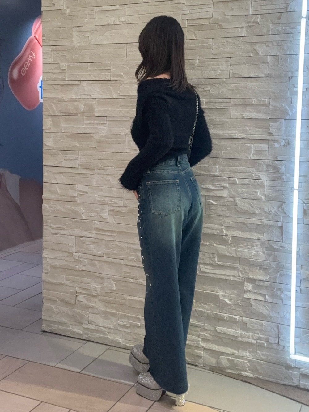 ブラック系のニット/セーター、ブルー系のデニムパンツ、ブラック系のショルダーバッグを着用したレディースの冬コーディネートの2枚目の写真