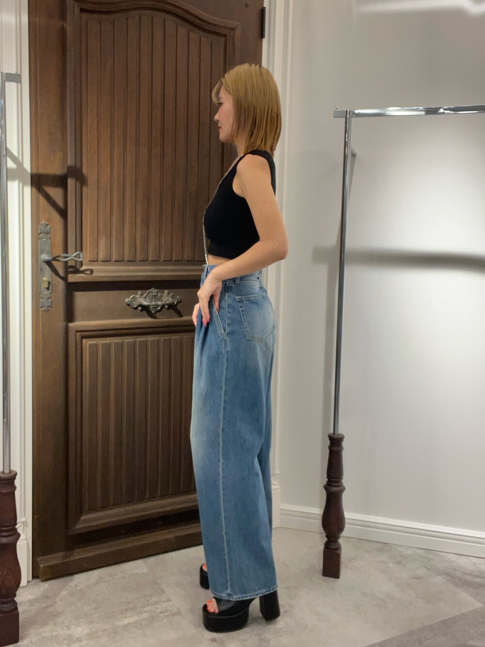 ブラック系のタンクトップ、ブルー系のデニムパンツ、グリーン系のショルダーバッグを着用したレディースの夏コーディネートの3枚目の写真