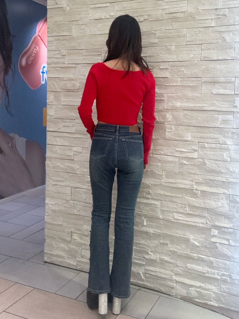 レッド系のニット/セーター、ブルー系のデニムパンツ、ブラック系のブーツを着用したレディースの冬コーディネートの3枚目の写真