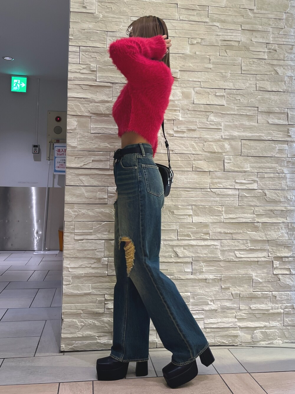 ピンク系のニット/セーター、ブルー系のデニムパンツ、ブラック系のショルダーバッグを着用したレディースの秋コーディネートの2枚目の写真