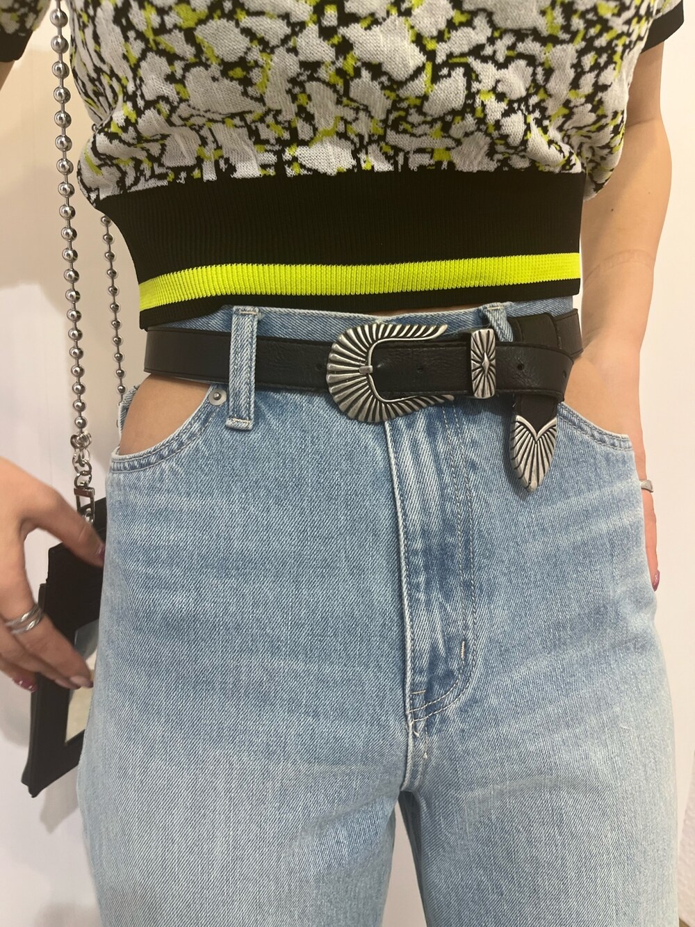 ブラック系のニット/セーター、ブルー系のデニムパンツを着用したレディースの春コーディネートの4枚目の写真